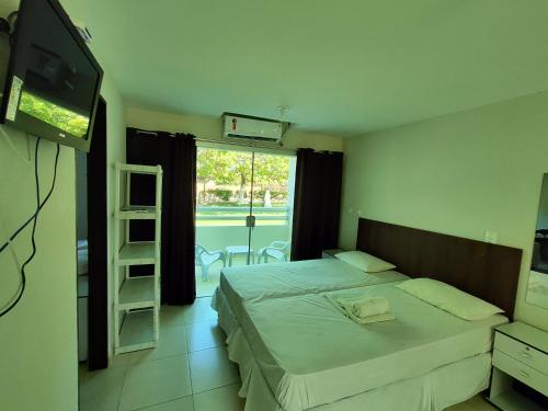 1 dormitorio con cama, TV y escalera en Divinos Flat Carneiros, en Praia dos Carneiros
