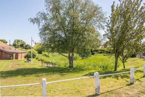 a fence with trees and a bench in a field at The Forge in Edgefield