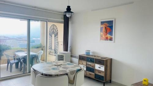 um quarto com uma mesa e uma sala de jantar com uma varanda em Appartement Les Asphodèles Calvi em Calvi