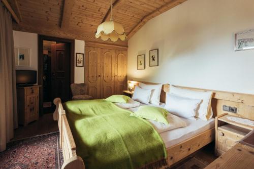 a bedroom with a bed with a green blanket on it at Haus Elisabeth in Santa Gertrude nella Val d'Ultimo