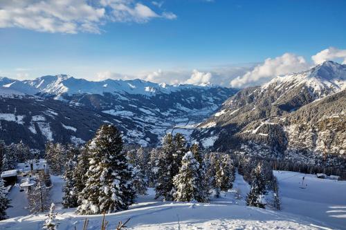 a snowy mountain with trees and snow covered mountains at Design Hotel Miramonte in Bad Gastein