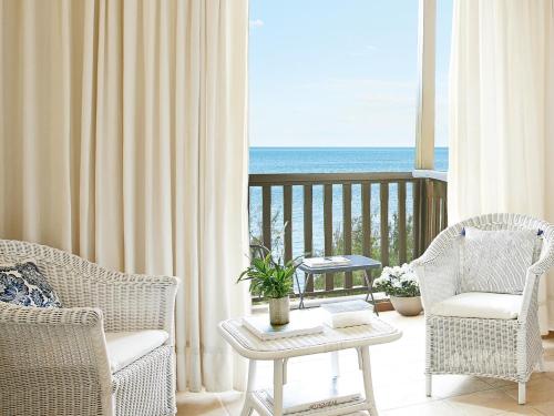 a living room with chairs and a balcony with the ocean at Grecotel Marine Palace & Aqua Park in Panormos Rethymno