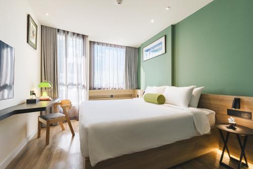 a bedroom with a large white bed and a desk at MO Hotel Bangkok in Bangkok