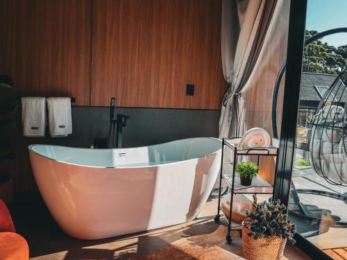 a bath tub in a bathroom with a window at Celeiro Lake Village - Soft Opening in São Francisco de Paula
