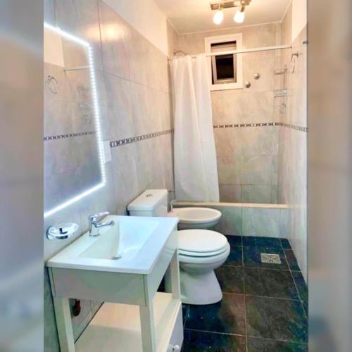 a white bathroom with a toilet and a sink at Loft Tempo in Esquel