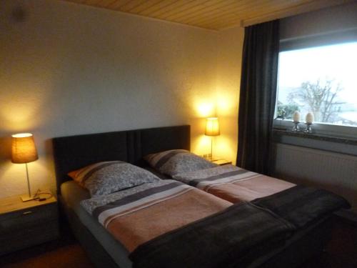 two beds in a bedroom with two lamps and a window at Ferienwohnungen Alpenblick mit Garten und Terrasse in Kirchdorf im Wald