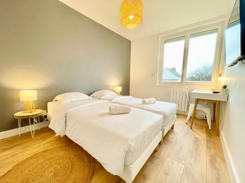 une chambre avec deux lits et un bureau et une fenêtre dans l'établissement Le Bohème 21 - Proche Gare - Fibre - Lumineux, à Saint-Nazaire