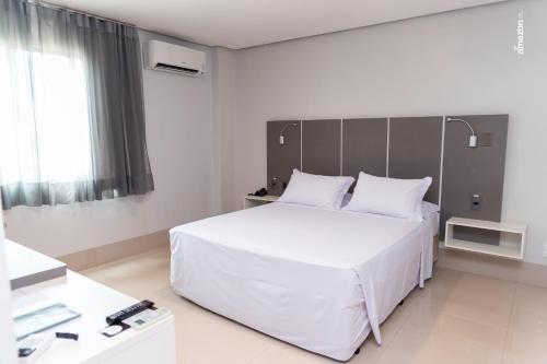 um quarto com uma grande cama branca e uma janela em Pumma Business Hotel em Canaã dos Carajás