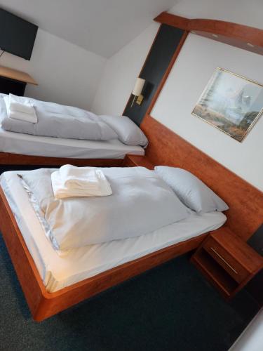 2 camas en una habitación de hotel con sábanas blancas en Hotel Heidekrug in Pinneberg, en Appen