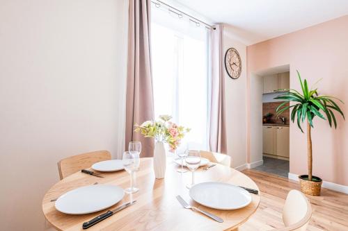 une salle à manger dotée d'une table avec des plaques et des chaises blanches dans l'établissement Idéal Pro et Famille en Hypercentre - 3 lits, à Corbeil-Essonnes