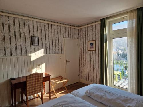 a bedroom with a bed and a desk and a window at Harz Hotel Waldhaus in Goslar