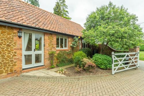 a brick house with a white gate in front of it at The Old Cow Shed in Grimston