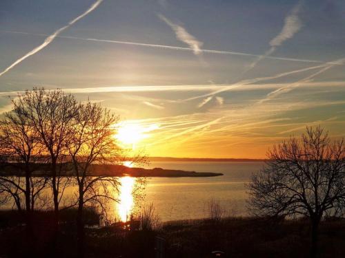 einen Sonnenuntergang über einem Wasserkörper mit Bäumen in der Unterkunft Seaside - ABC415 in Wismar