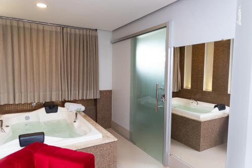 a bathroom with a tub and a sink at Pumma Business Hotel in Canaã dos Carajás