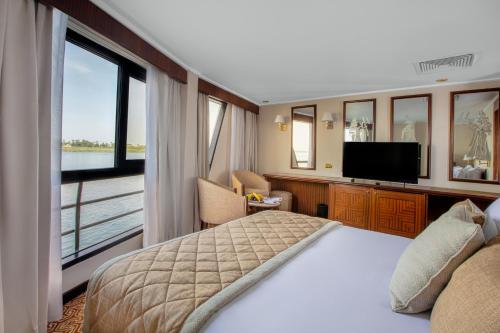 a bedroom with a large bed and a television at Jaz Celebrity Nile Cruise - Every Saturday from Luxor for 07 & 04 Nights - Every Wednesday From Aswan for 03 Nights in Luxor