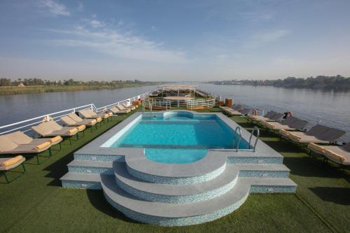 a boat on a river with a pool and chairs at Jaz Celebrity Nile Cruise - Every Saturday from Luxor for 07 & 04 Nights - Every Wednesday From Aswan for 03 Nights in Luxor