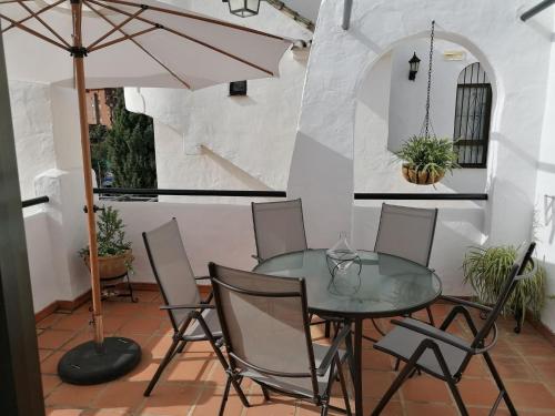 eine Terrasse mit einem Glastisch und Stühlen und einem Sonnenschirm in der Unterkunft 1 Bedroom Apartment in Pueblo Evita in Arroyo de la Miel