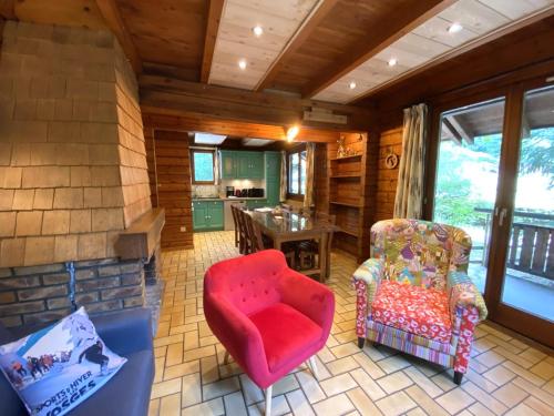 Una sala de estar con una silla roja y una mesa. en LE SKIEUR Chalet en bois, en La Bresse