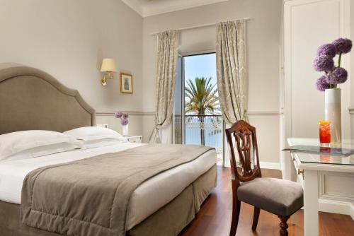 a bedroom with a bed and a desk and a window at Royal Hotel Sanremo in Sanremo