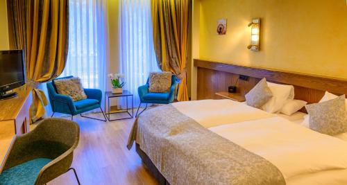 a hotel room with two beds and two chairs at Hotel Brimer in Grundhof