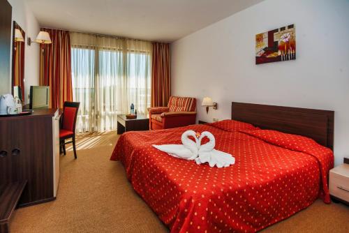 a hotel room with a red bed with a flower on it at Hermes Club Hotel - Ultra All Inclusive in Tsarevo