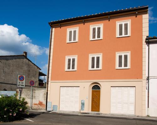 un edificio naranja y blanco con puertas blancas de garaje en Tana Dell'Orso, en Ponsacco