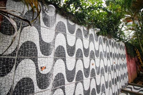 un mur en mosaïque avec un motif d’onde sur celui-ci; dans l'établissement Farah Camping Smartcamp hospedagem econômica, à Boicucanga