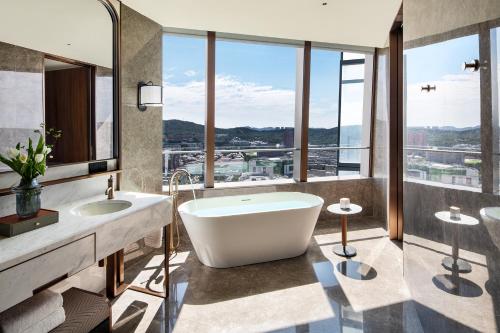 a bathroom with a tub and two sinks and windows at Four Seasons Hotel Dalian in Dalian