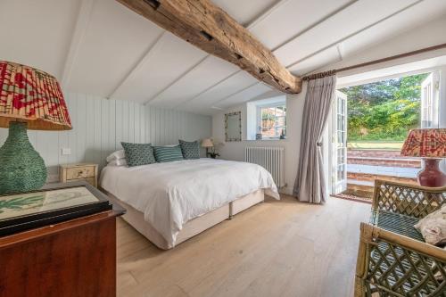 a bedroom with a bed and a large window at The Long Cottage in Flitcham