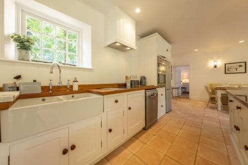 a kitchen with white cabinets and a large sink at The Long Cottage in Flitcham