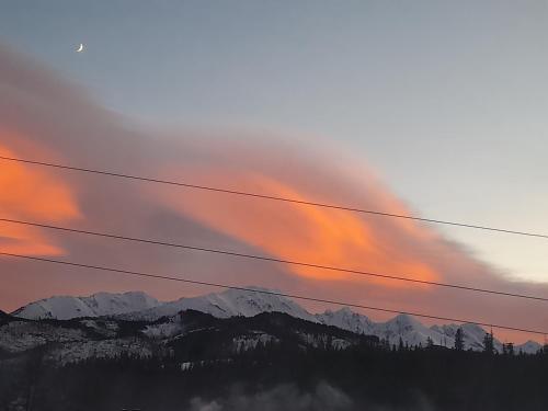 a sunset with power lines in front of a mountain at Domki nad Borem in Male Ciche