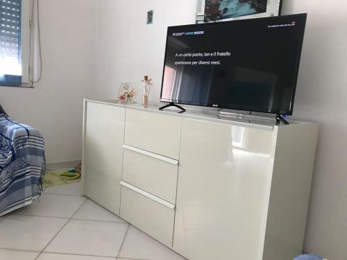 TV de pantalla plana en la parte superior de un armario blanco en Comfort Home, en Capoterra