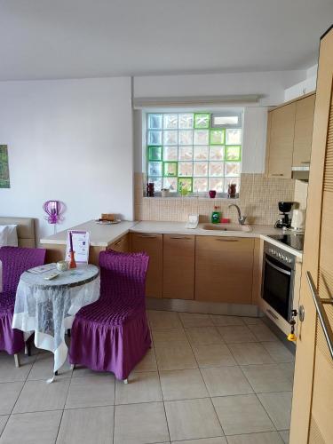 a kitchen with purple chairs and a table and a window at Δροσια 1 in Nafplio