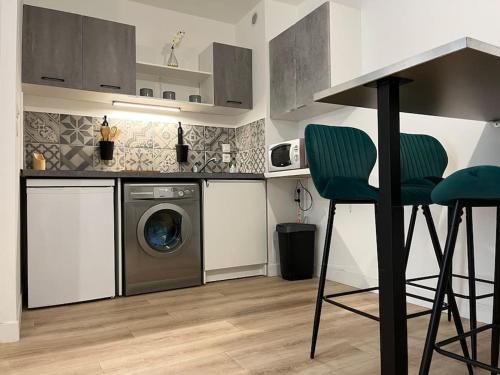 una cucina con lavatrice e 2 sedie verdi di Appartement rénové, 3mns à pied de la gare ad Alès