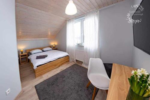 a bedroom with a bed and a table and a window at Karłowski Przesmyk in Grabowo