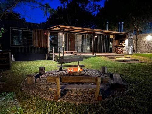 una hoguera con una mesa de picnic en un patio por la noche en Casa a 30 metros de la playa, en Ciudad de la Costa