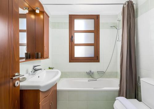a bathroom with a sink and a tub and a toilet at Lindos Aeonian Villas in Líndos