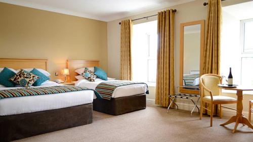 a hotel room with two beds and a desk at Cill Aodain Court Hotel in Kiltimagh