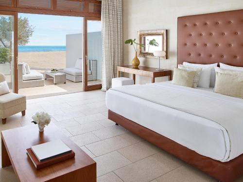 a bedroom with a large bed and a view of the beach at Amirandes, A Grecotel Resort to Live in Gouves