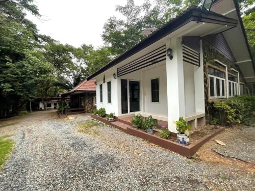 a house with a gravel driveway in front of it at Baan Rai Somkiat Homestay Saraburi in Ban Lam Thong Lang