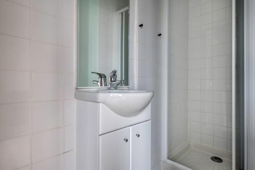 une salle de bain blanche avec un lavabo et un miroir dans l'établissement À 50m de la plage, Appartement vue mer, à La Plaine-sur-Mer