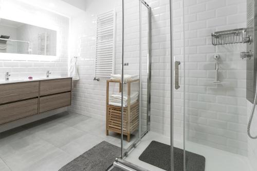 uma casa de banho branca com um chuveiro e um lavatório. em Casa Avós Félix Lopes na Foz do Arelho