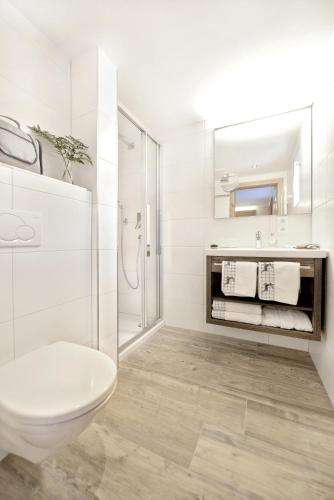 a white bathroom with a toilet and a sink at Hotel Alpina Superior in Pettneu am Arlberg