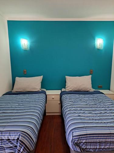 two beds in a room with a blue wall at Refugio de Caty in Bahía Mansa