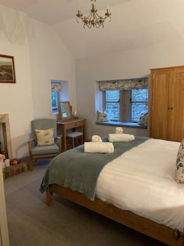 een slaapkamer met 2 bedden, een stoel en een kroonluchter bij Enchanting Cottage for 4- Witchnest in Derbyshire, with EV point in Bonsall