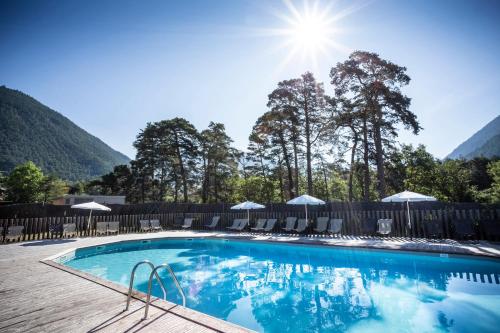 a swimming pool with mountains in the background at Huttopia Bourg St Maurice in Bourg-Saint-Maurice