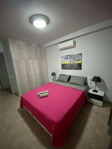 a bedroom with a pink bed with a pink blanket at CENTRAL APARTMENT PORTOHELI 1 in Porto Heli