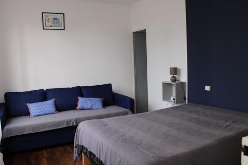 een woonkamer met een blauwe bank en een bed bij 480 - Maison de pêcheur à 50m de la Plage de Caroual 