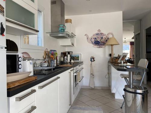 une cuisine avec des armoires blanches et un comptoir noir dans l'établissement 487 - Maison T3, sur la plage de Caroual, à Caroual