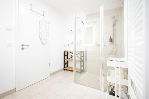 uma casa de banho branca com um chuveiro e um lavatório. em Ko-Living - Yellow Submarine Suite - Altstadt - Küche - 2 SZ - getrennte Betten - bis 7 Gäste em Halle an der Saale
